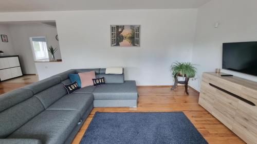 a living room with a gray couch and a flat screen tv at Apartament Riviera z widokiem na kanał Augustowski in Augustów