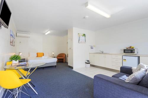a living room with a couch and a table and a kitchen at Top Spot Motel in Maroochydore