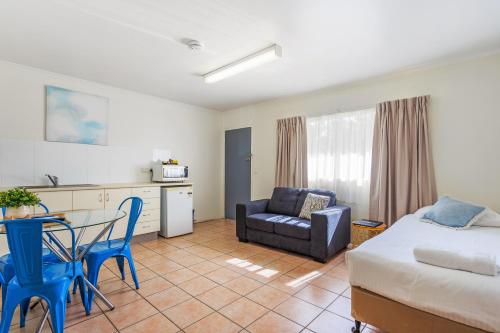 a room with a bed and a table and a kitchen at Top Spot Motel in Maroochydore
