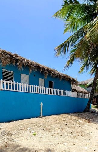 a blue house with a straw roof and a palm tree at La Casita de Mary in Santa Cruz de Barahona