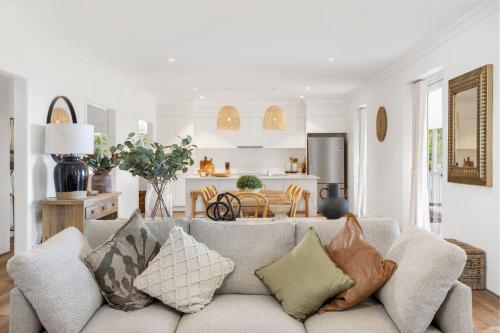 ein Wohnzimmer mit einer grauen Couch mit Kissen in der Unterkunft Willow House Gerringong in Rose Valley