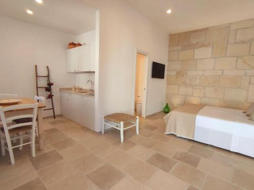 ein Schlafzimmer mit einem Bett und einem Tisch sowie eine Küche in der Unterkunft La Noscia - Le Dimore di Thesia in Otranto