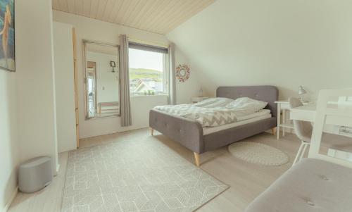 a bedroom with a bed and a desk and a window at Great 3 BR Loft Apt / Views / Free Parking in Tórshavn