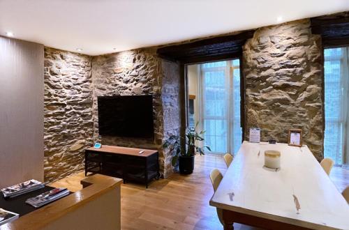 a room with a stone wall with a table and a television at Luxury Arquillos Vitoria in Vitoria-Gasteiz