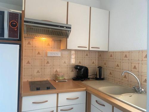 une petite cuisine avec des armoires blanches et un évier dans l'établissement Appartement Cosy à 300m de la Plage, Parking Privé, Loggia Fermée, 4 Pers., 2 Étoiles - FR-1-225-758, à Argelès-sur-Mer