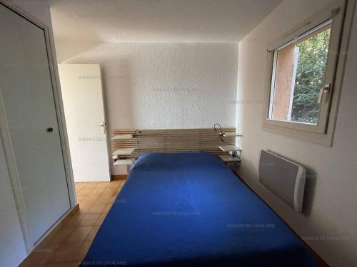 ein großes blaues Bett in einem Zimmer mit Fenster in der Unterkunft Rez-de-jardin T2 avec terrasse et parking - FR-1-100-284 in Rayol-Canadel-sur-Mer