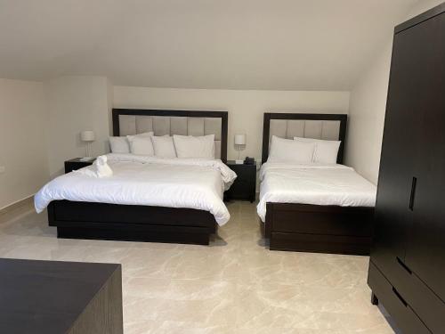 a bedroom with two beds with white sheets at Mizirawi Historic Hotel in Ramallah