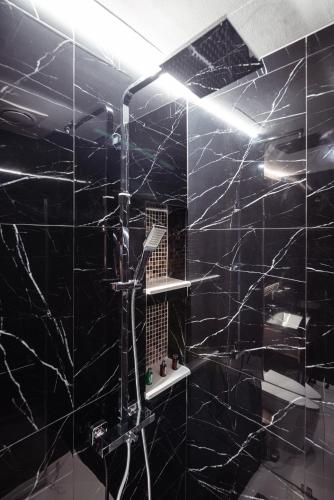 a bathroom with a shower with black marble walls at The One Smart Living in Bangkok