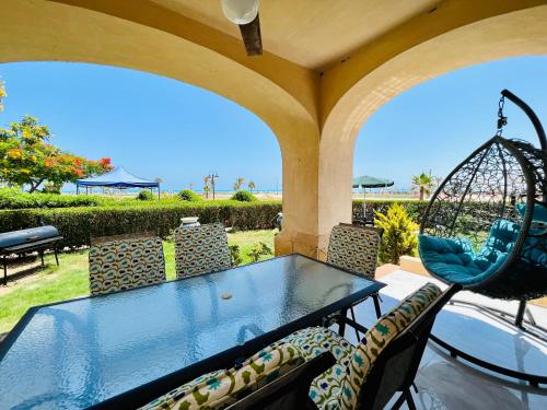 una mesa y sillas en un patio con vistas al océano en Lazorde Beachfront Experience, en El Alamein