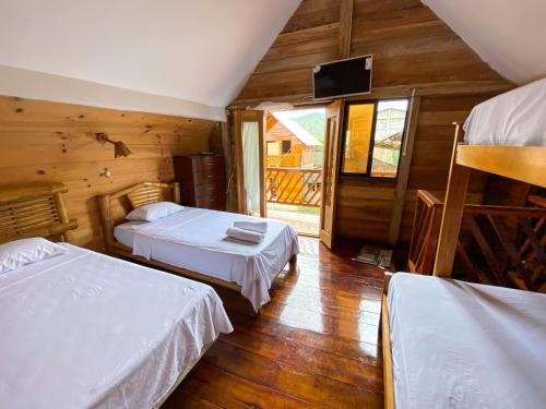 a bedroom with two beds and a television in a cabin at Hostal Tortuga Dorada in Puerto López