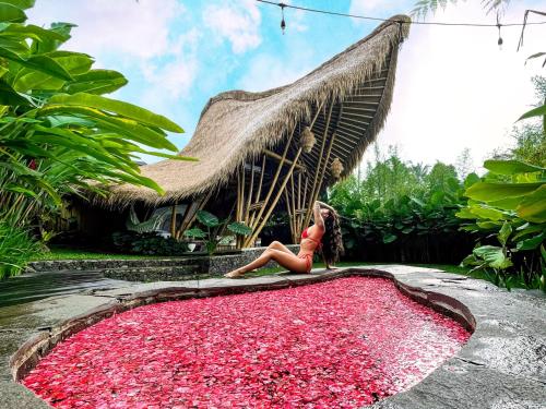 a woman sitting on a large pile of red flower petals at Balikayanas Bamboo House - Miggiell House in Karangasem