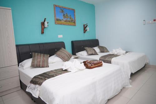 three beds in a room with a blue wall at Langkawi Country Lodge2 in Pantai Cenang