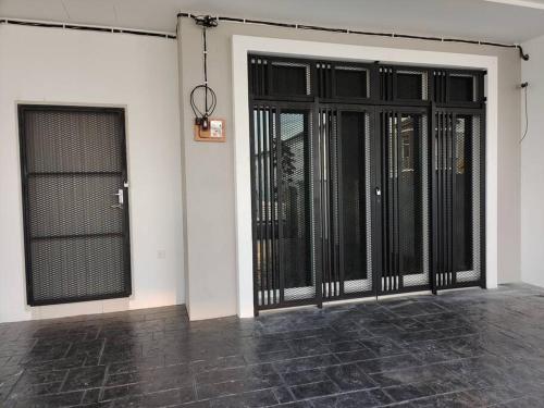 um quarto com portas pretas no lado de um edifício em The Dandelion Homestay em Baling