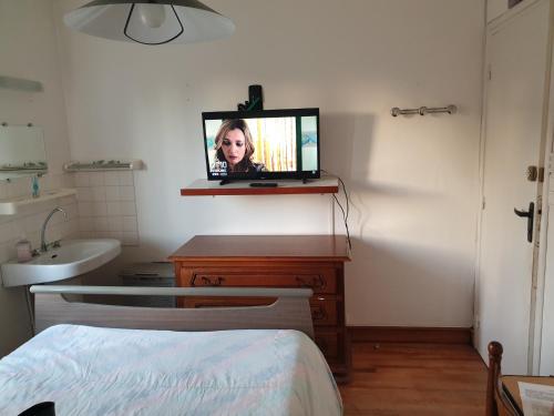 1 dormitorio con TV en un tocador con cama en villa des clématites, en Dainville