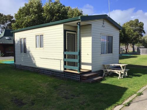 a white tiny house with a picnic table in a yard at North Arm Tourist Park in Lakes Entrance