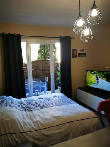 - une chambre avec un lit, une télévision et un balcon dans l'établissement Appartement Indépendant dans le Résid hôtel idéal pour les vacances - séminaires - déplacements pro 