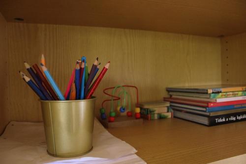 a cup filled with pens and pencils next to books at Lovely Nest near Budapest in Dunakeszi