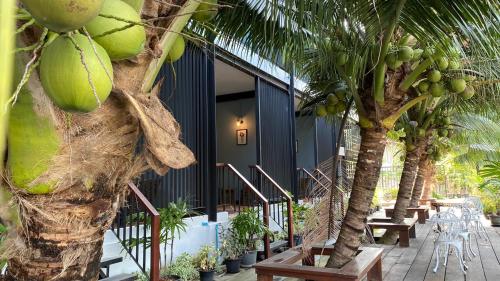 a building with palm trees and tables and chairs at Maikaew Damnoen Resort in Damnoen Saduak