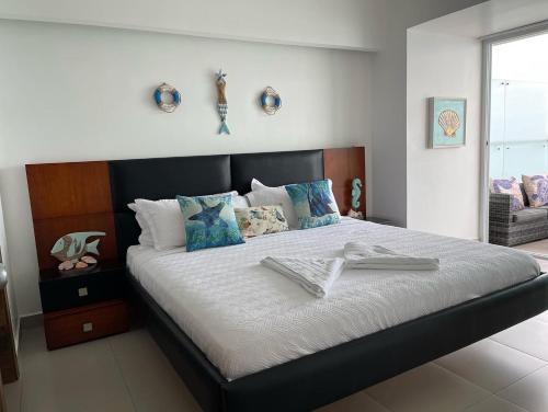 a bedroom with a large bed with white sheets and blue pillows at Departamentos frente al mar in Tonsupa