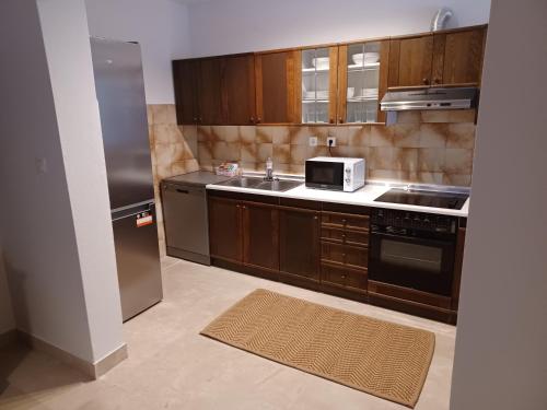uma cozinha com armários de madeira, um lavatório e um micro-ondas em Apartments Andrea em Jesenice