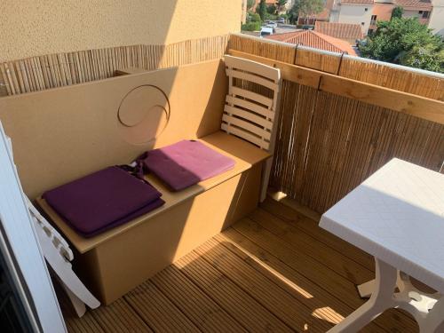 un balcón con una mesa y cojines morados. en La Vigie du Corsaire, en Carqueiranne