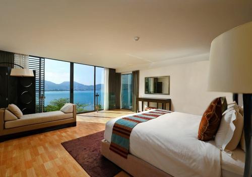 Indochine Resort and Villas - SHA Extra Plus في شاطيء باتونغ: غرفة نوم بسرير كبير ومطلة على الماء