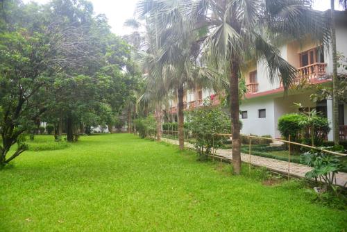 a green yard in front of a building at Chitwan Paradise Hotel in Sauraha