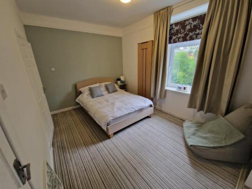 a bedroom with a bed and a window and a chair at Milne Apartment 1 in Milnrow