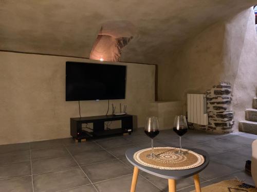 ein Wohnzimmer mit 2 Weingläsern und einem TV in der Unterkunft LE BOISÉ GÉNILOIS- Campagne-Chic-Climatisé in Genilac
