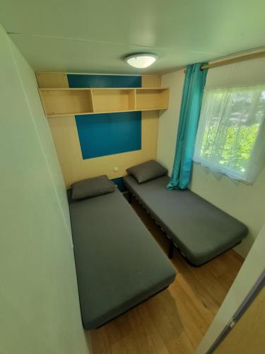 Habitación pequeña con 2 camas y ventana en Mobil-home 6 personnes climatisé le Miami, en Saint-Chéron
