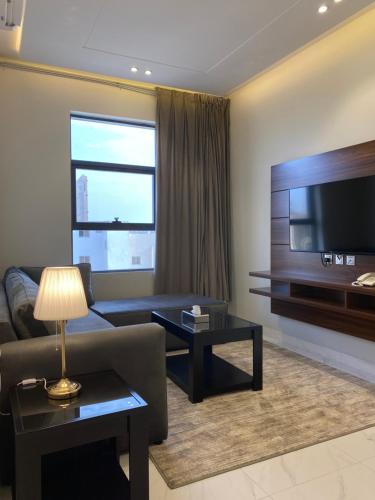 a living room with a couch and a flat screen tv at فخامة المشارف للشقق المخدومة in Abha