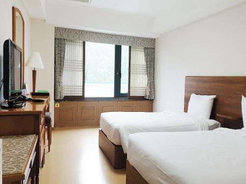 a hotel room with two beds and a television at The K Hotel Gyeongju in Gyeongju