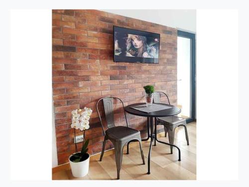- un mur en briques avec une table et des chaises dans la chambre dans l'établissement Piata Victoriei Sanador Studio Apartment, à Bucarest