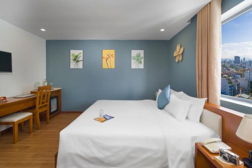 a bedroom with a bed and a desk and a window at Merry Land Hotel Da Nang in Da Nang
