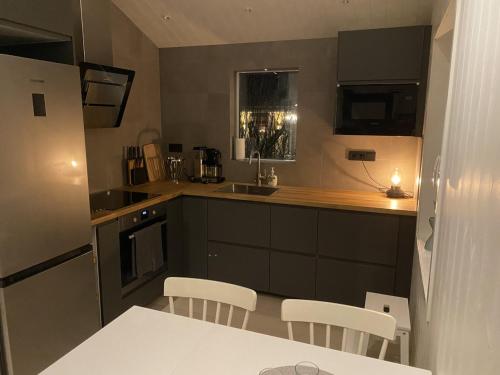 una cocina con armarios negros y una mesa y sillas blancas. en Ekberg Annexet en Järvsö