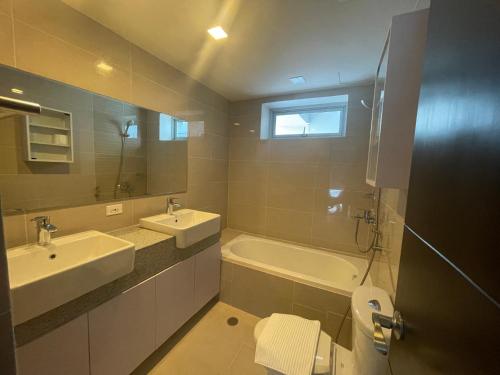 a bathroom with two sinks and a tub and a toilet at Bright 2-bedroom condo with pool in BGC Uptown in Manila