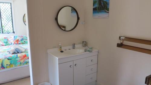a bathroom with a sink and a mirror and a bed at Mirabel Cottage in Arcadia