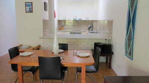 a wooden table with black chairs and a kitchen at Magnetic Reef 7 in Arcadia