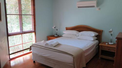 Un dormitorio con una cama con sábanas y almohadas blancas. en Kameruka, en Arcadia