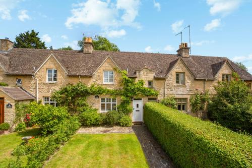 an old stone house with a hedge at Clover Cottage in Wyck Rissington