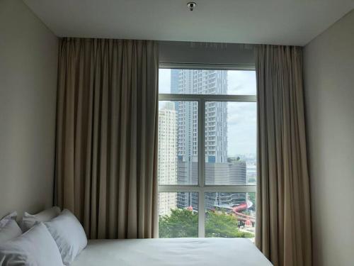 a bedroom with a large window with a view of a city at Central Park Residences (2BR - 22nd Floor) in Jakarta