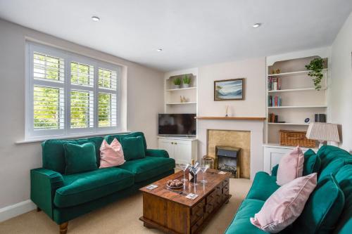 a living room with two green couches and a fireplace at Clover Cottage in Wyck Rissington