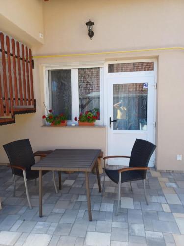 a patio with a table and chairs and a window at Bé-La 2 Vendégház in Szomolya
