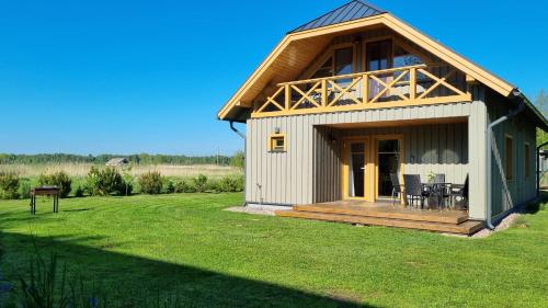 a small cottage with a deck on a lawn at Smiltinas in Nidden