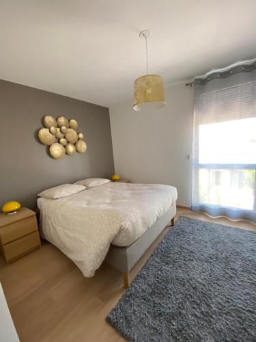 1 dormitorio con cama, ventana y alfombra en Au coeur des volcans et lacs d'Auvergne, en Saint-Beauzire