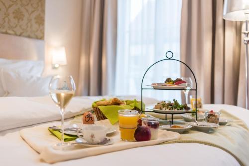 a breakfast tray with food and drinks on a bed at Romantik Hotel Reichshof in Norden
