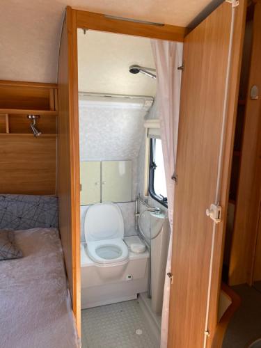 a small bathroom with a toilet in an rv at Słoneczne Przyczepy Dębki in Dębki