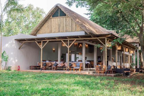 una casa con sillas y mesas en el porche en Adrift River Club, en Kangulumira