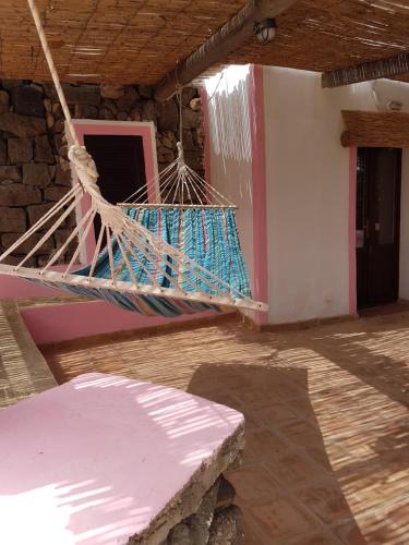 a porch with a hammock hanging from a house at dammusi 2 in Pantelleria