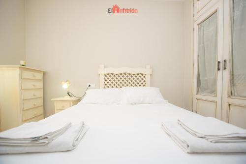 Un dormitorio con una cama blanca y una cómoda. en El Anfitrión - Dúplex Doña Ana, en Sanlúcar de Barrameda